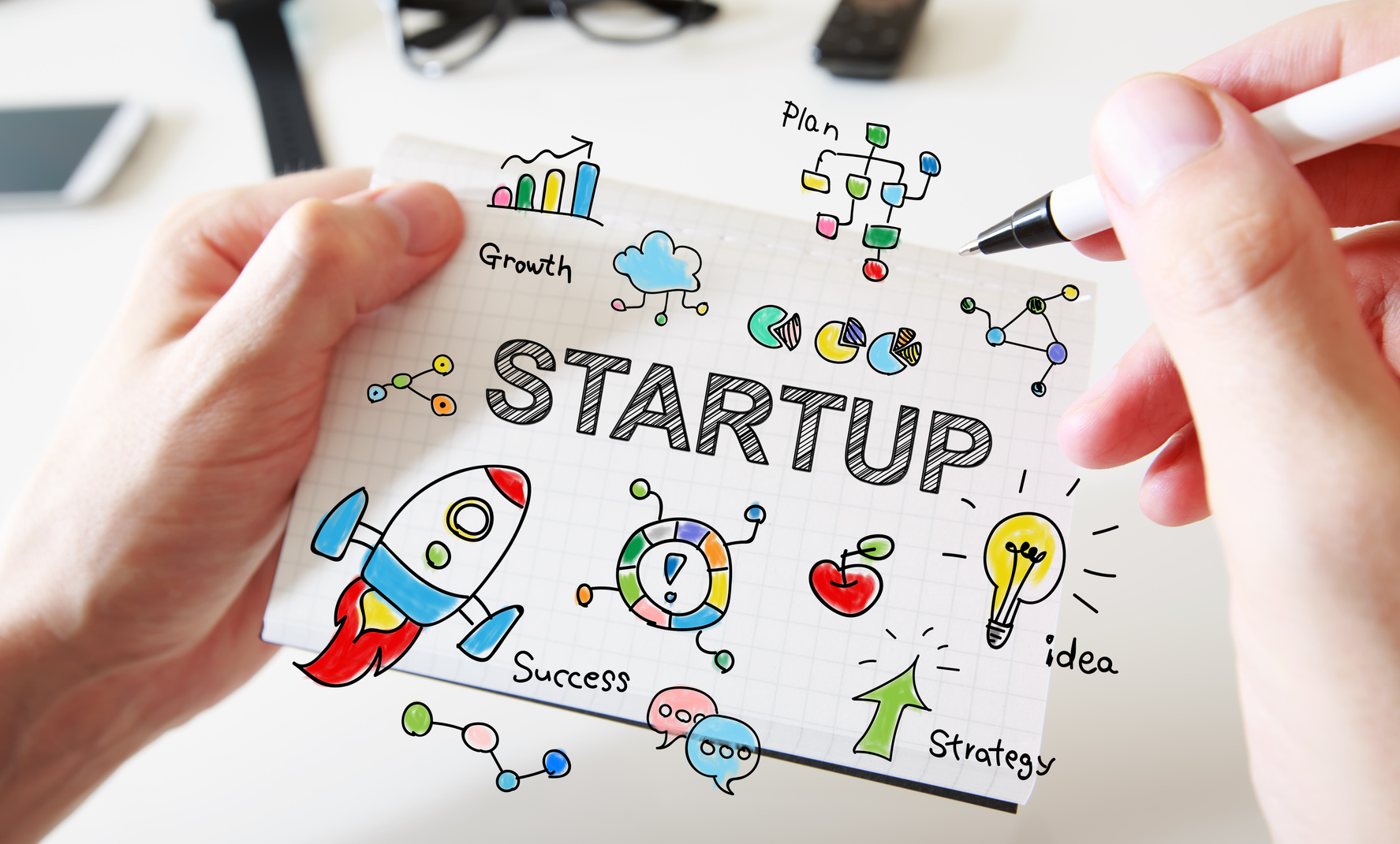 Mans hand drawing Startup concept on notebook